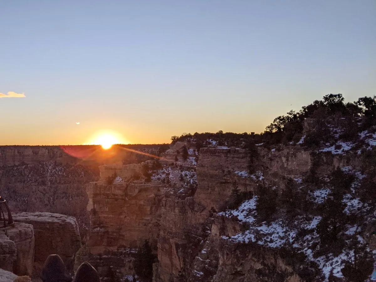 Sun rising over a snow-dusted canyon rim